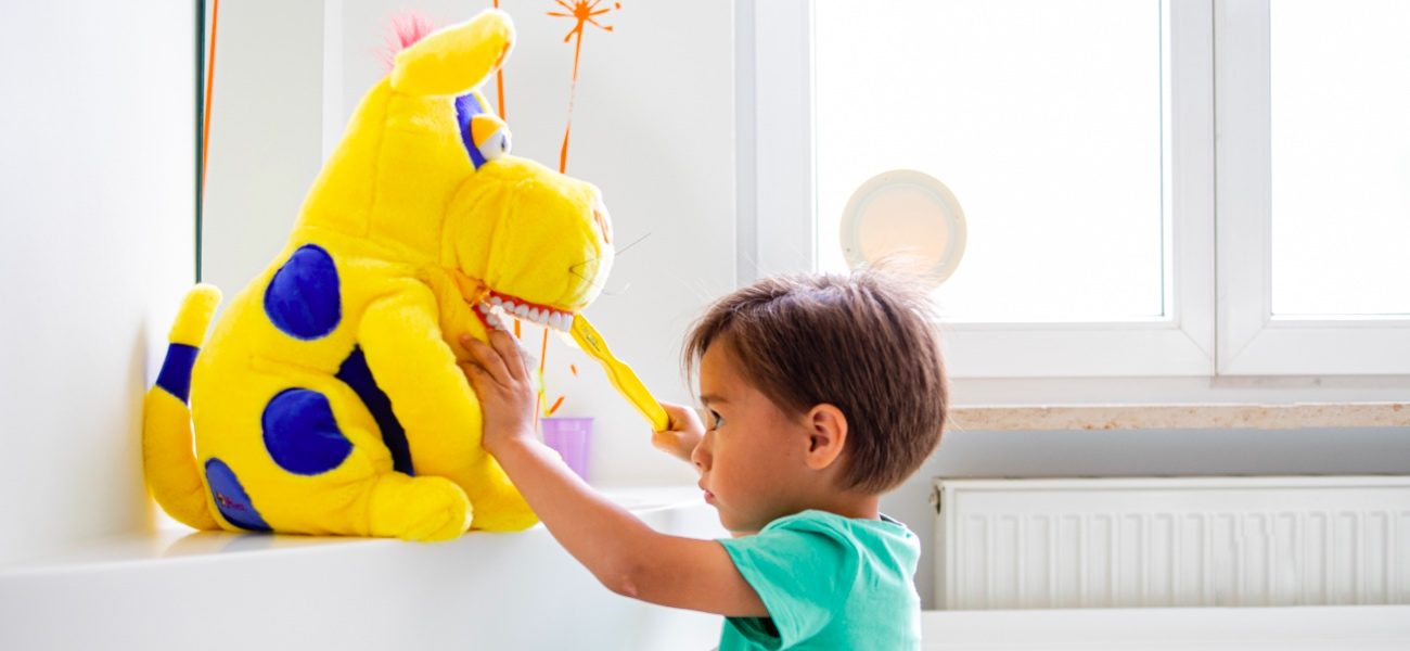 Kind übt Zähneputzen an Kuscheltier